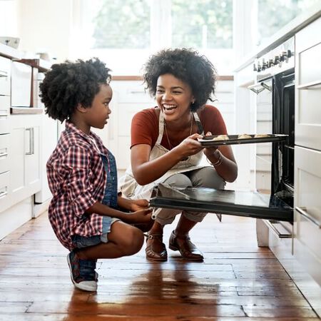 Woman and child taking cookies out of the oven