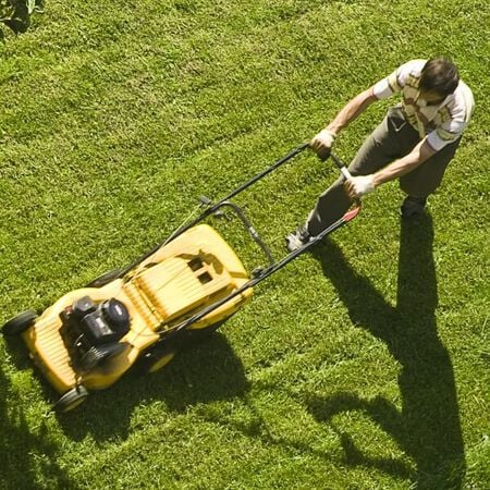 Man mowing lawn with a yellow motorized lawn mower
